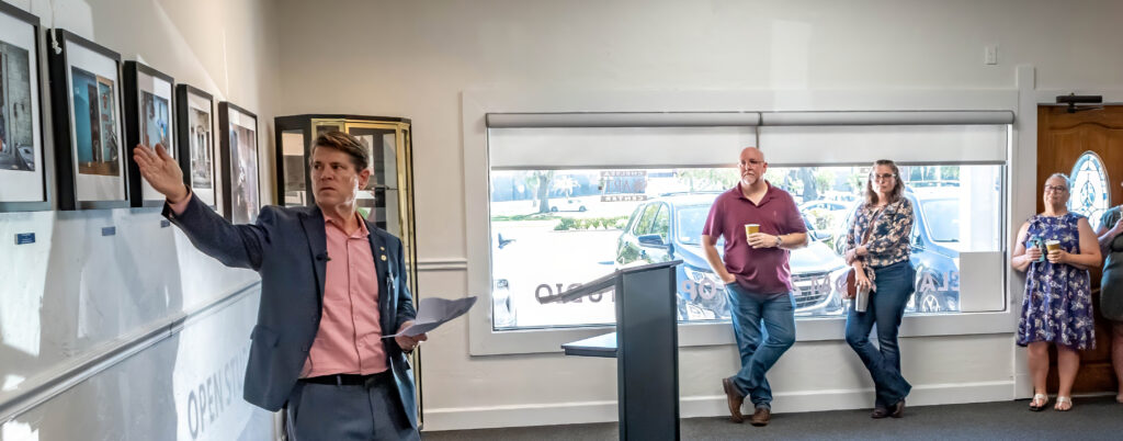 International Photography Exhibit Opening Reception Talk- John Elliott expounds on a photograph in the "Walls and Spaces" exhibit area.